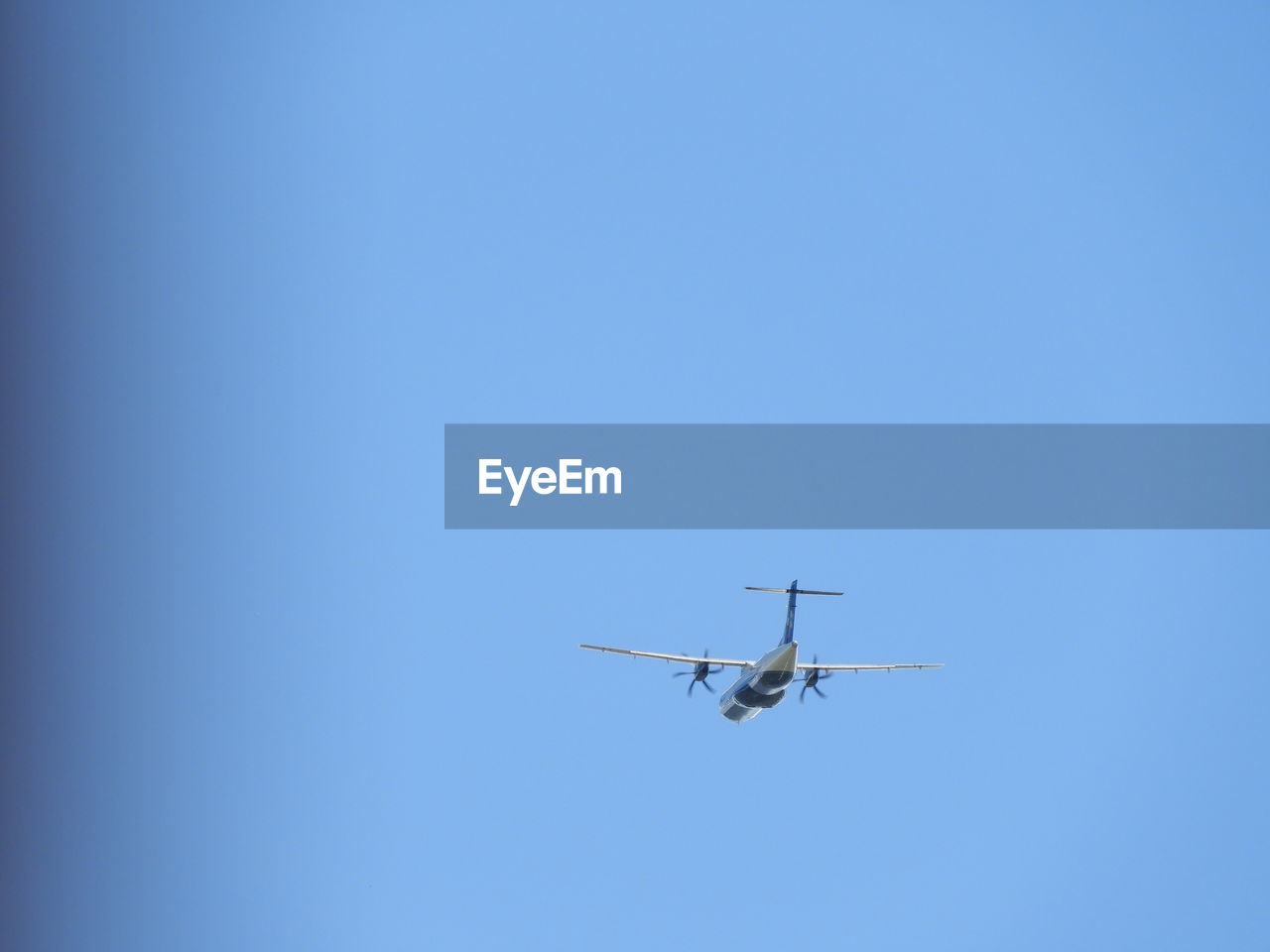 Low angle view of airplane flying against clear blue sky