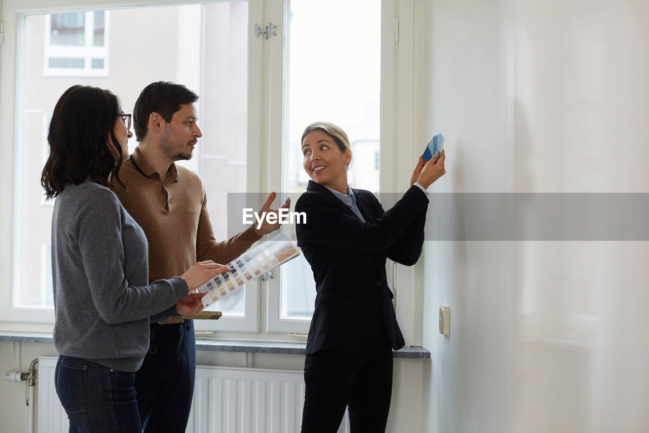 Real estate agent showing color samples to couple in new home