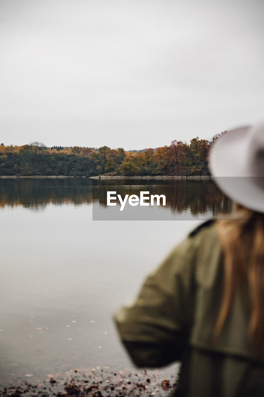 Rear view of woman standing against lake