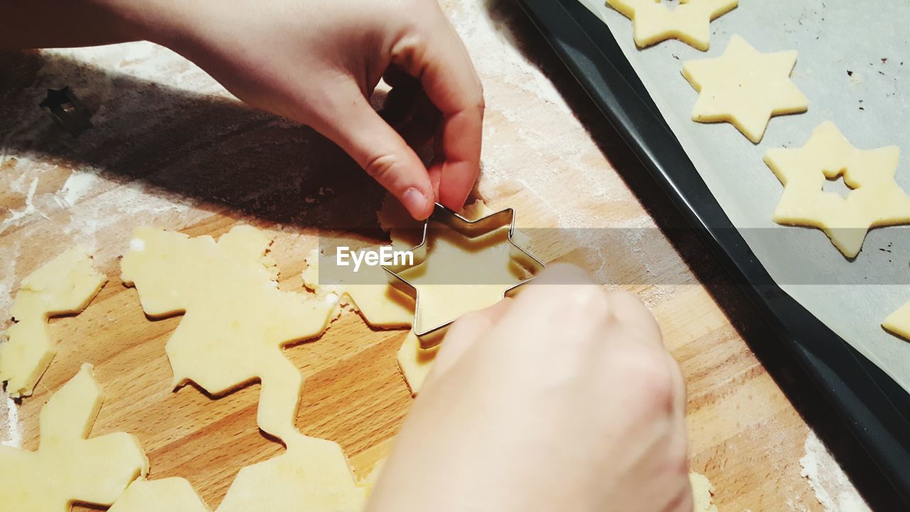 Cropped hands preparing cookies on cutting board