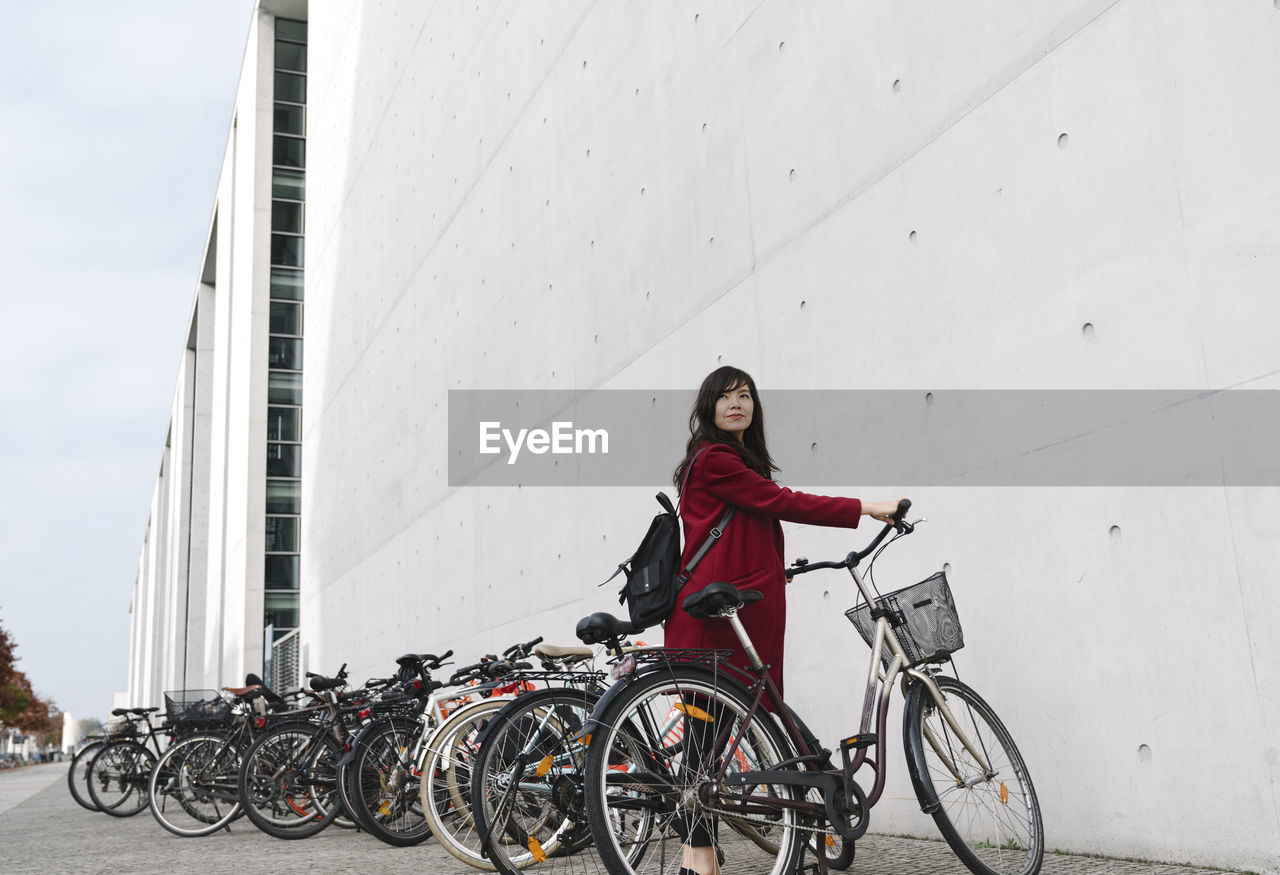 Businesswoman taking bicycle in the background of modern building