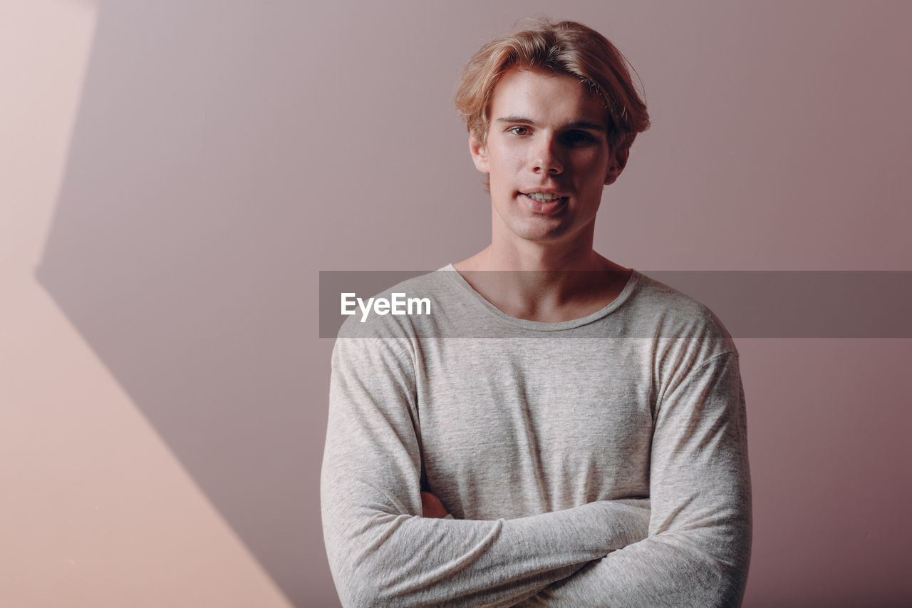 portrait of young man looking away against wall