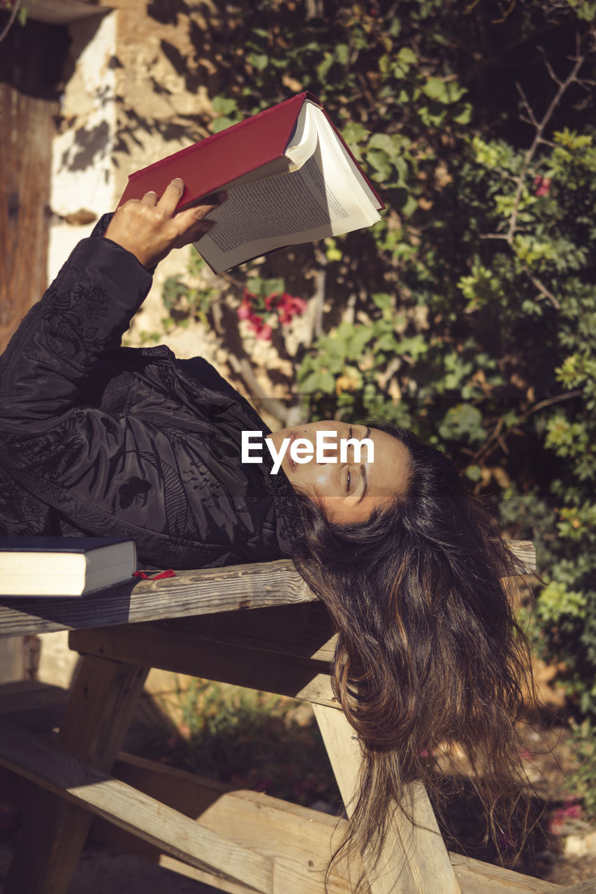 Beautiful woman reading in the garden, looking at the camera