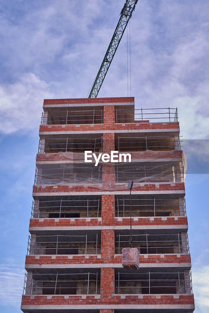 Views of a crane working on the lifting of materials during the construction of a protection house