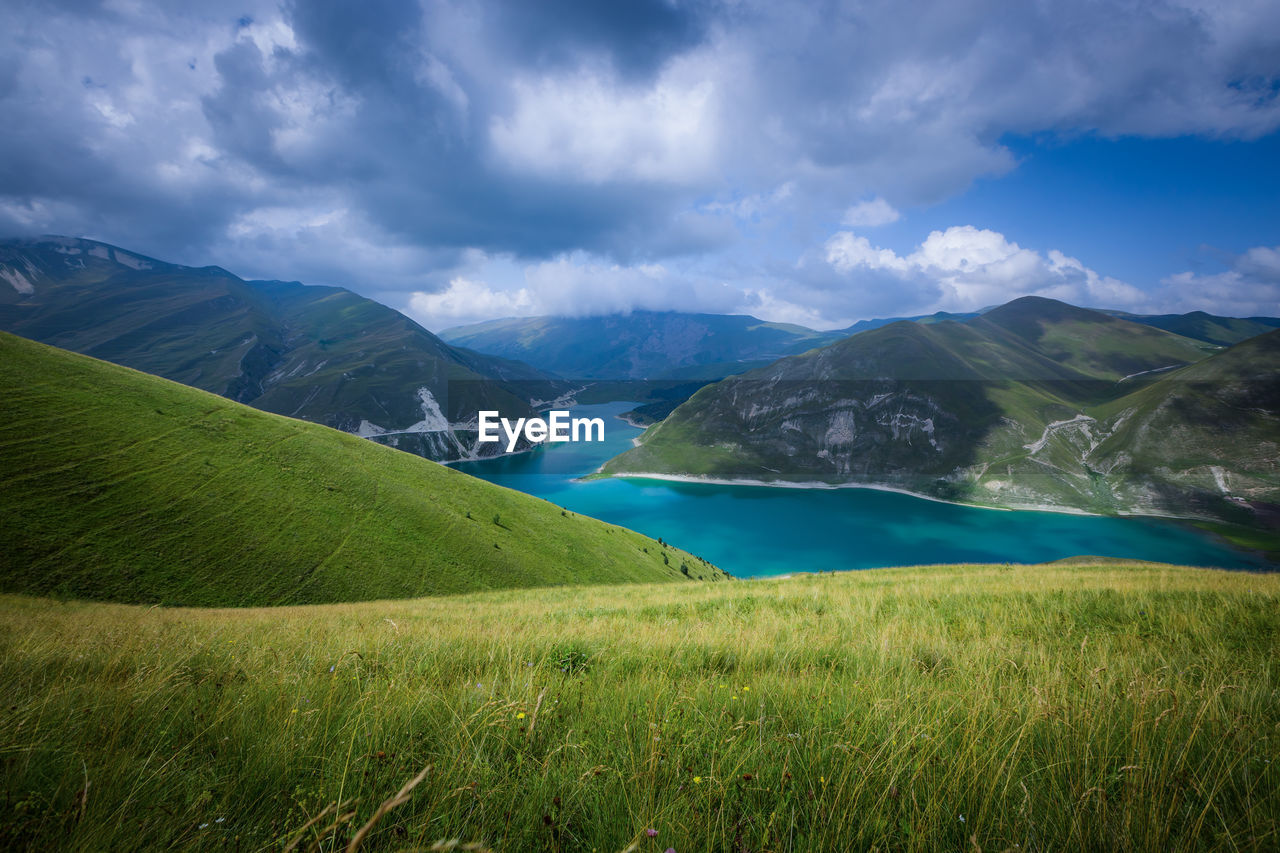 Lake kezenoy am in the green mountains. scenic view of landscape and mountains against sky