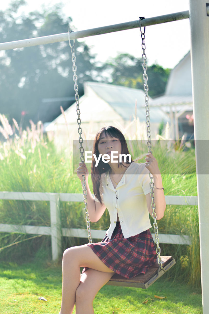 portrait of young woman swinging at playground