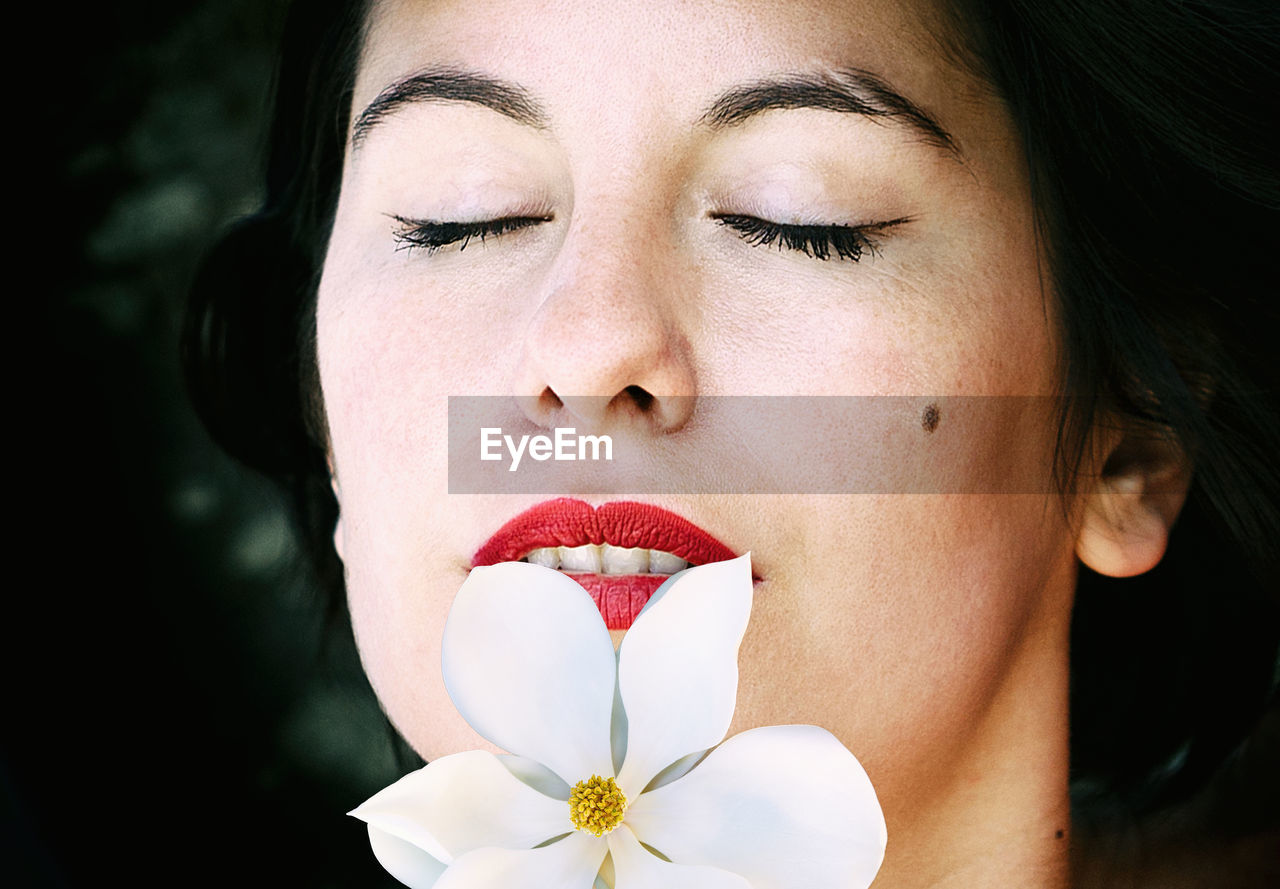 Woman with closed eyes and a magnolia tree on her lips