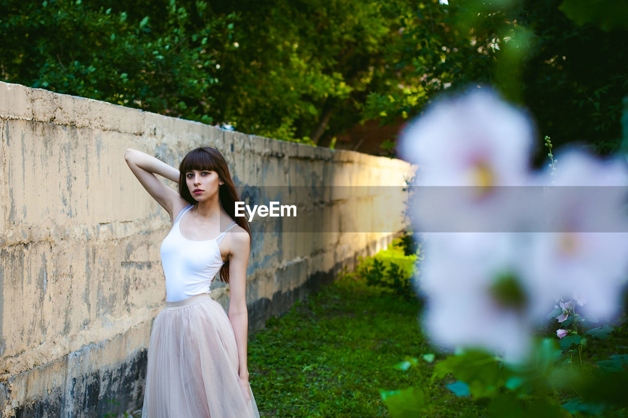 Close-up of flowers against young woman standing at park