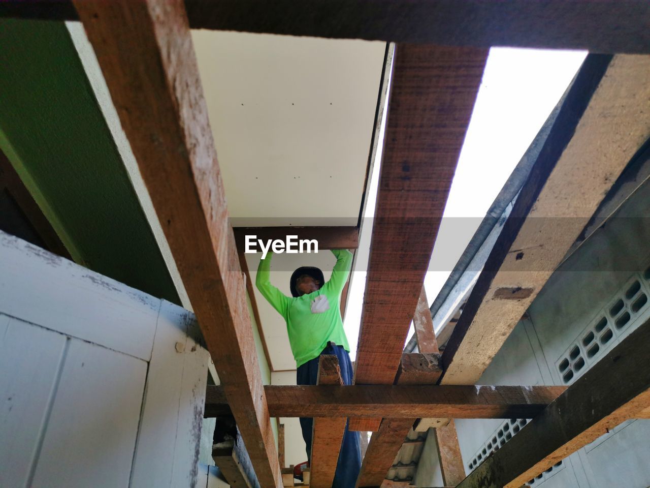 LOW ANGLE VIEW OF MAN STANDING BY WINDOW