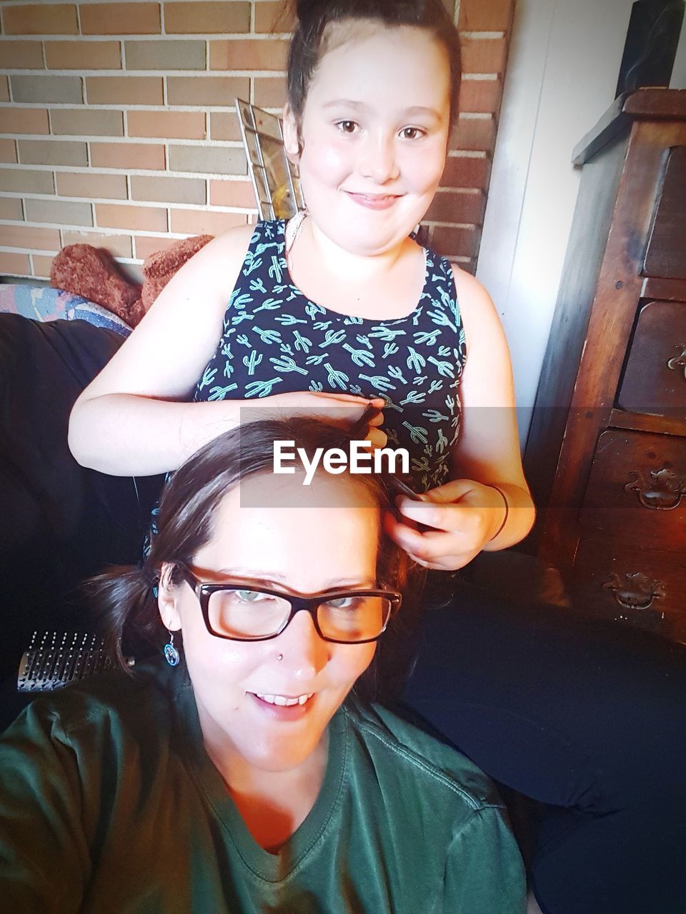 Portrait of smiling daughter tying mother hair at home