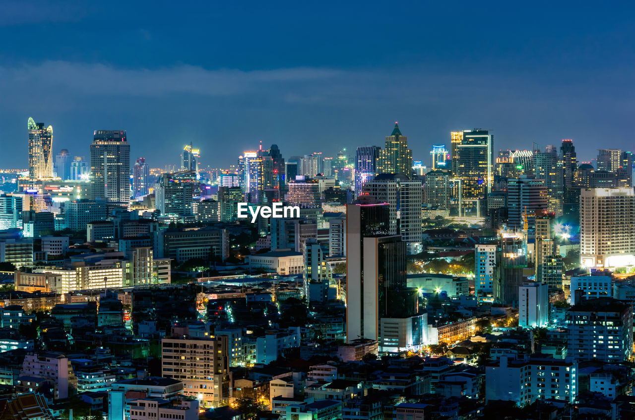 Illuminated buildings in city against sky