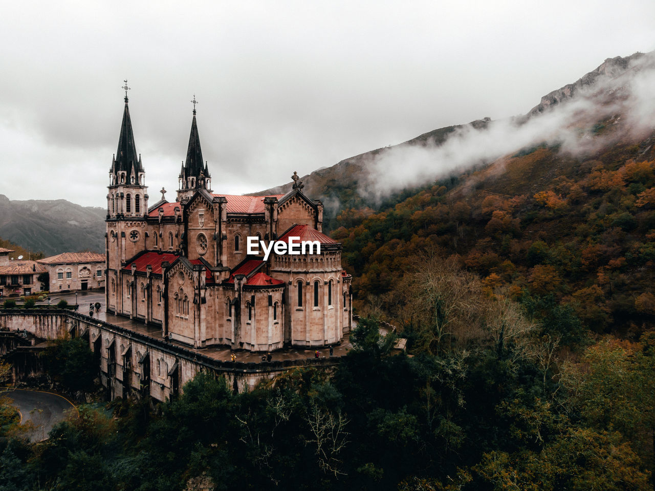 Historic basilica by mountain against cloudy sky