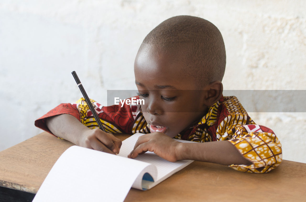 Close-up of boy writing in book on table