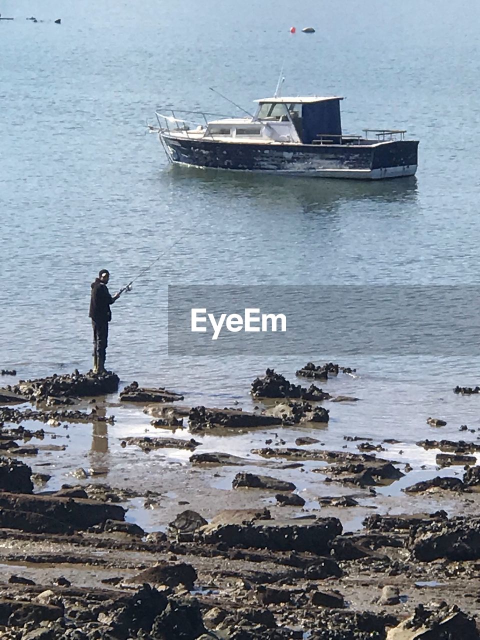 Man fishing at sea against sky