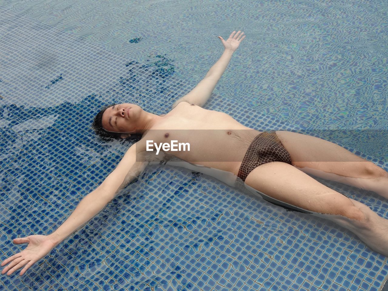 High angle view of man in underwear relaxing in swimming pool