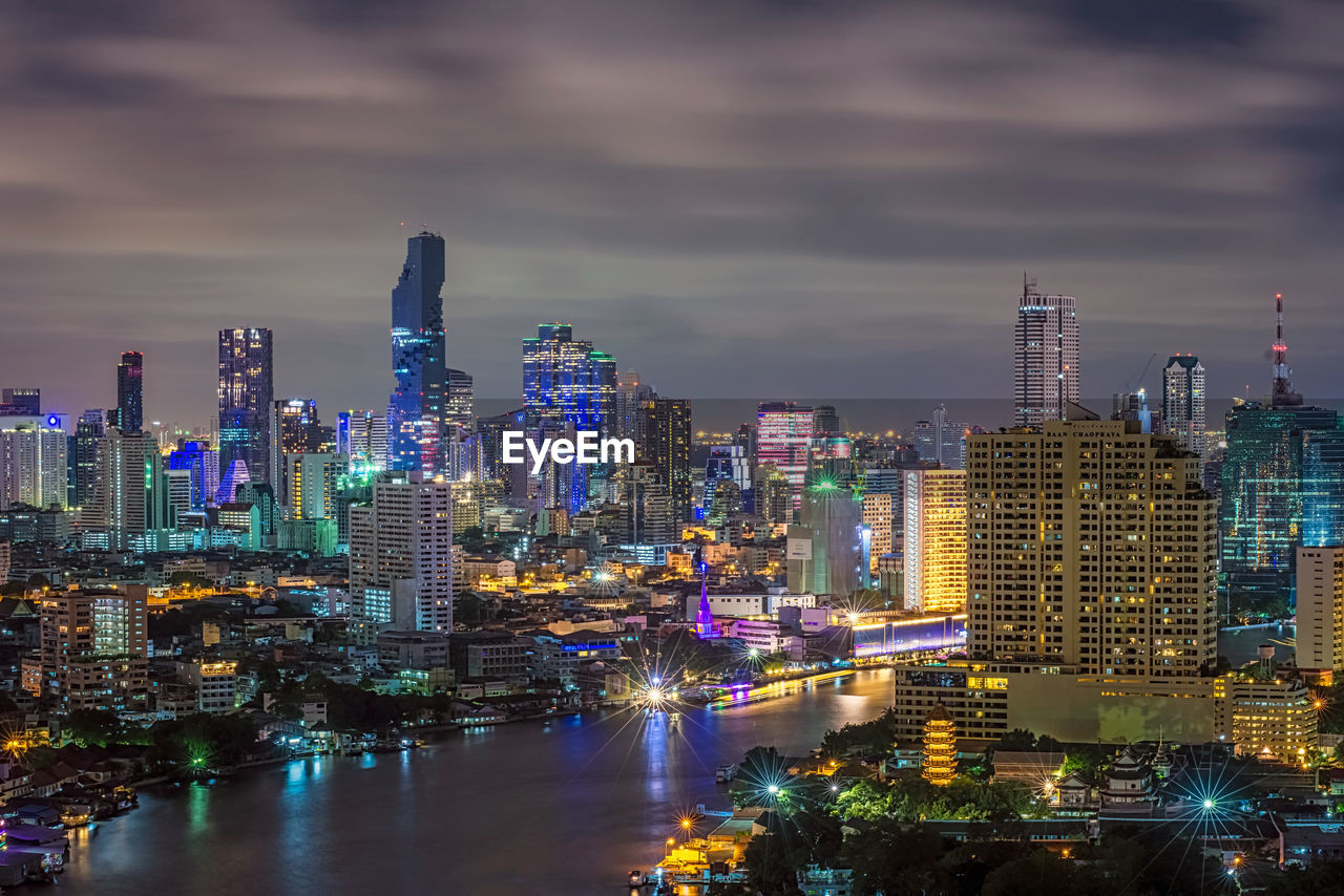 High angle view of chao phraya river amidst illuminated buildings in city