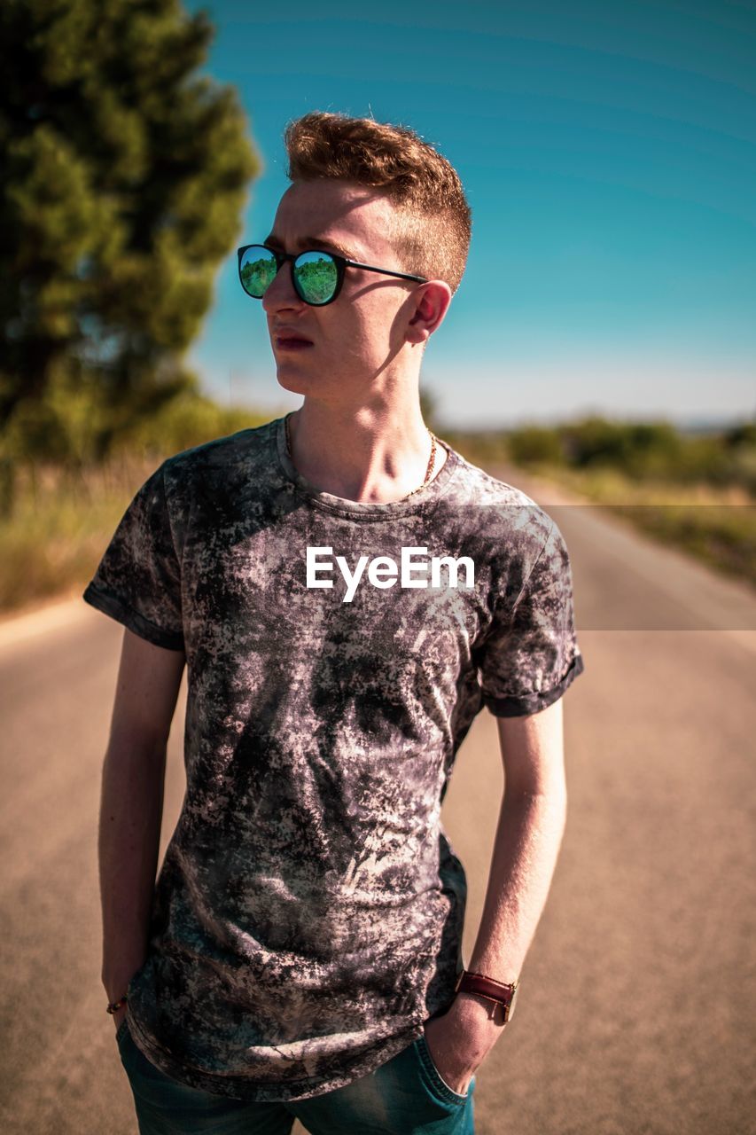 Young man standing on road against sky