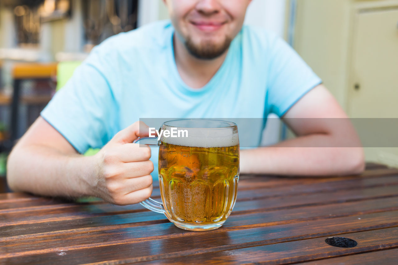 Midsection of man drinking glass on table