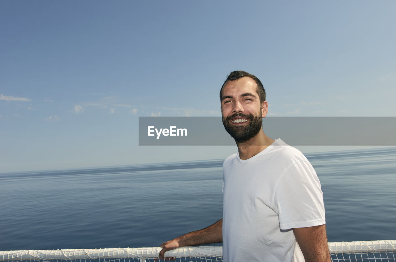 Portrait of smiling man standing by sea