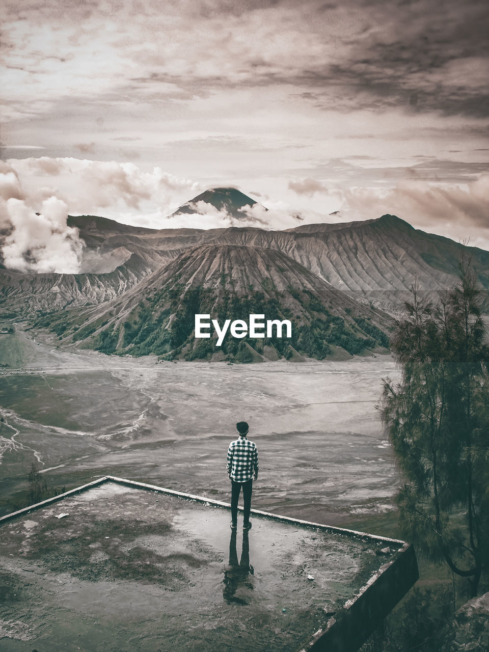 Rear view of man standing against mountain and cloudy sky