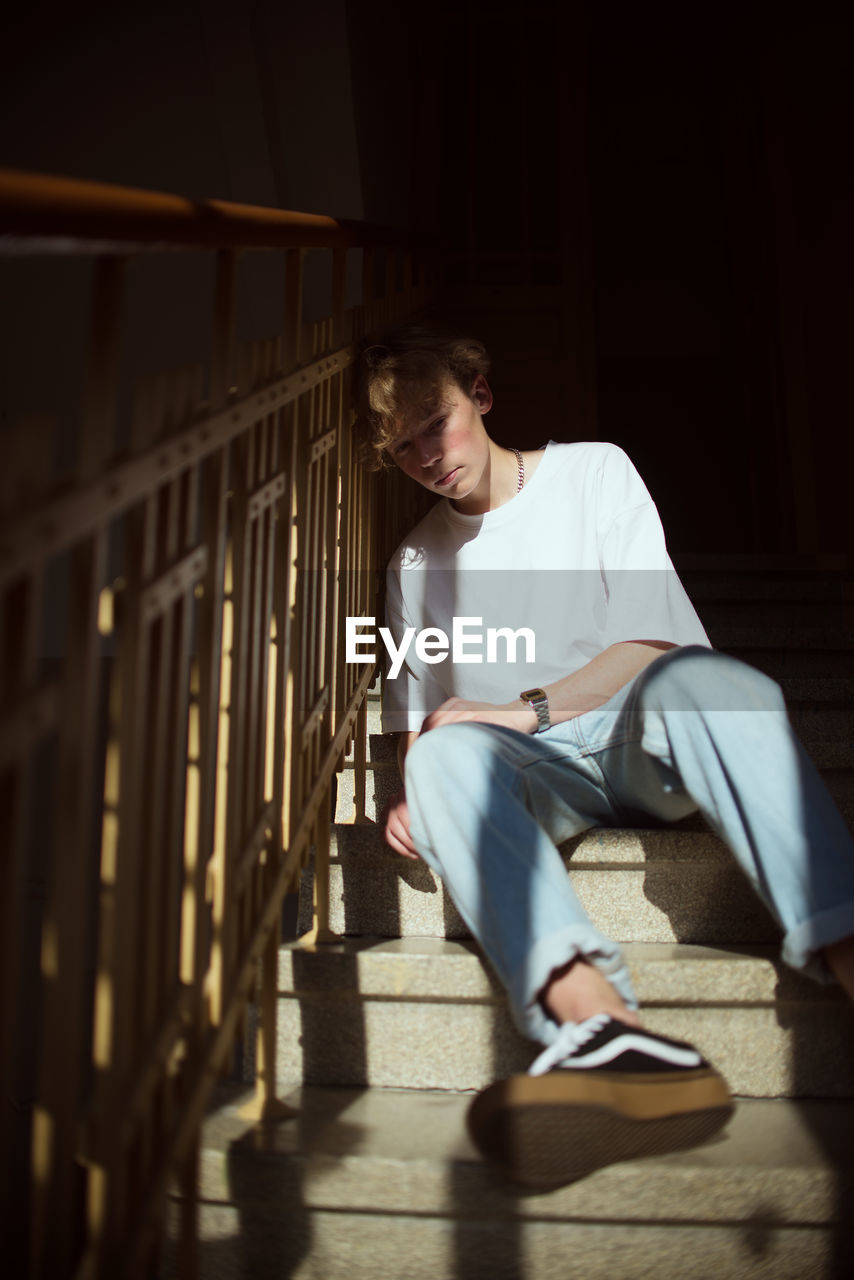 YOUNG MAN SITTING ON RAILING