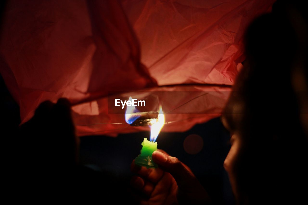 CLOSE-UP OF HANDS ON ILLUMINATED ELECTRIC LAMP