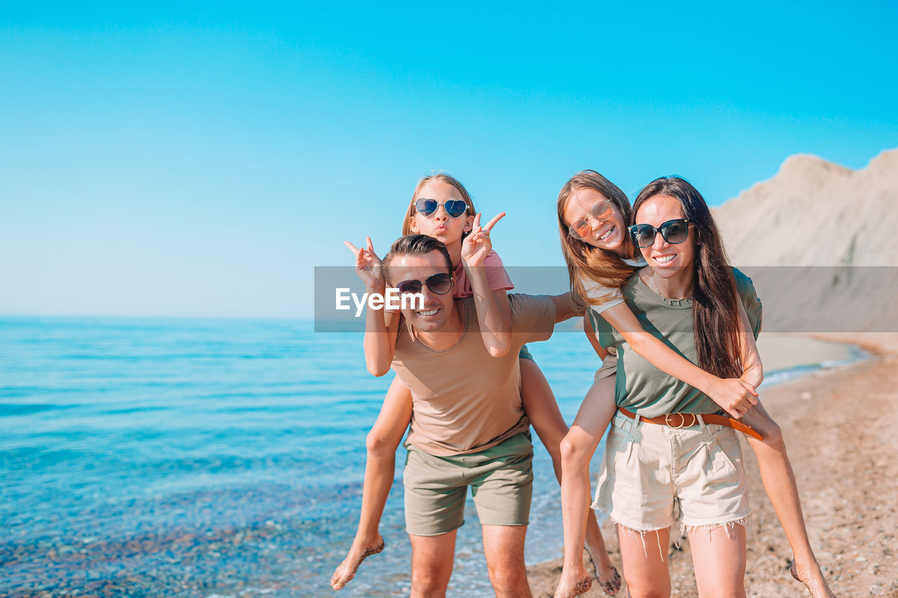 Portrait of friends standing by sea against sky