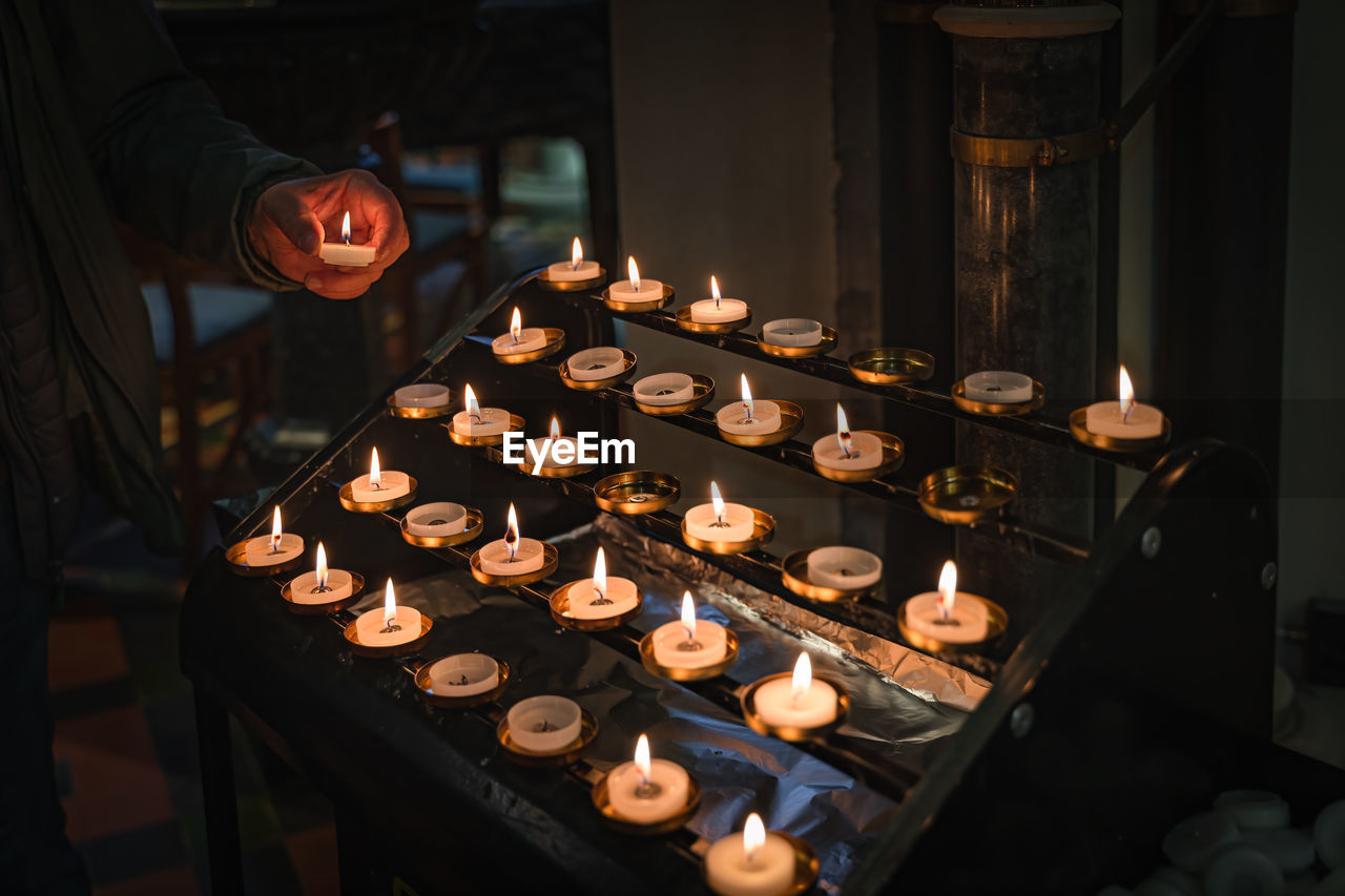 Mens hand holding a lit candle and putting it on altar, st. patricks cathedral, ireland