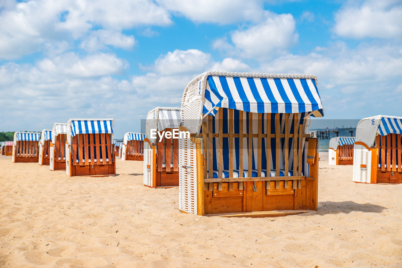 Hooded chairs on beach against sky