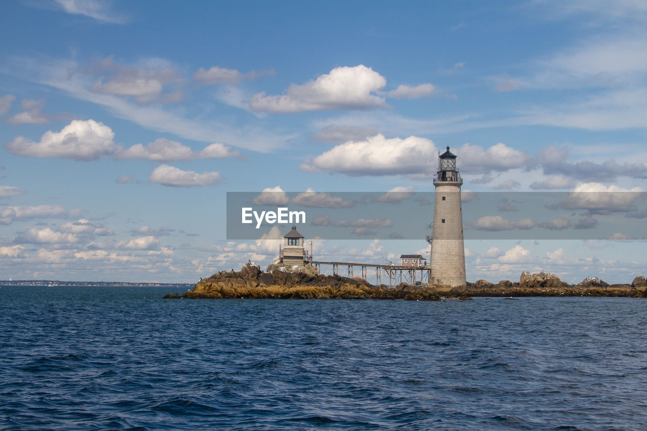 Lighthouse by sea against sky