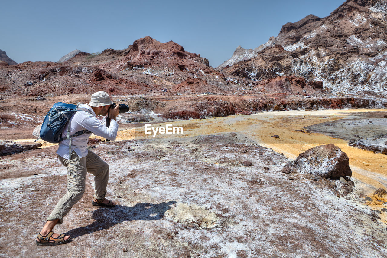 Full length of man photographing on rock