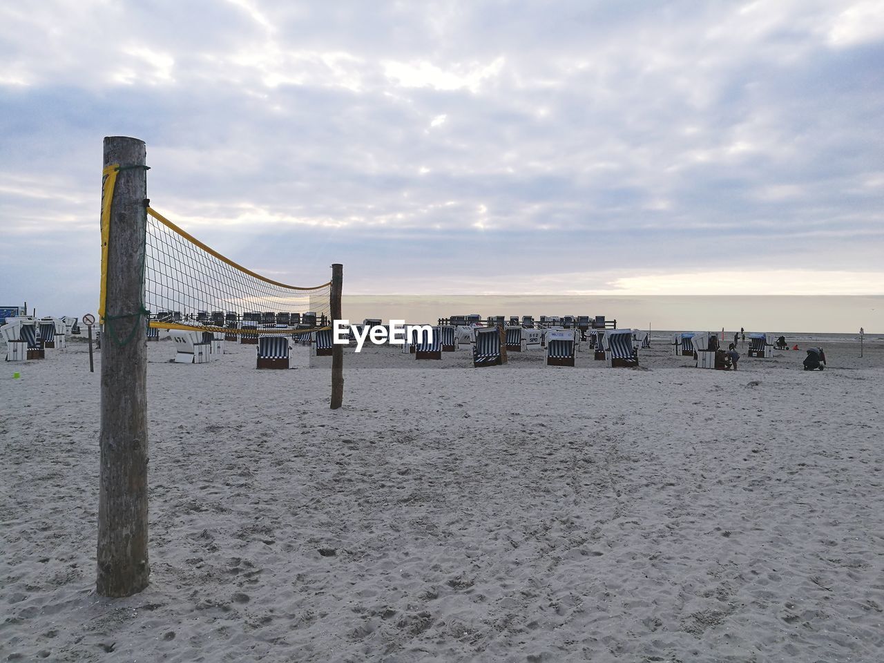 Wooden posts on beach against sky during sunset