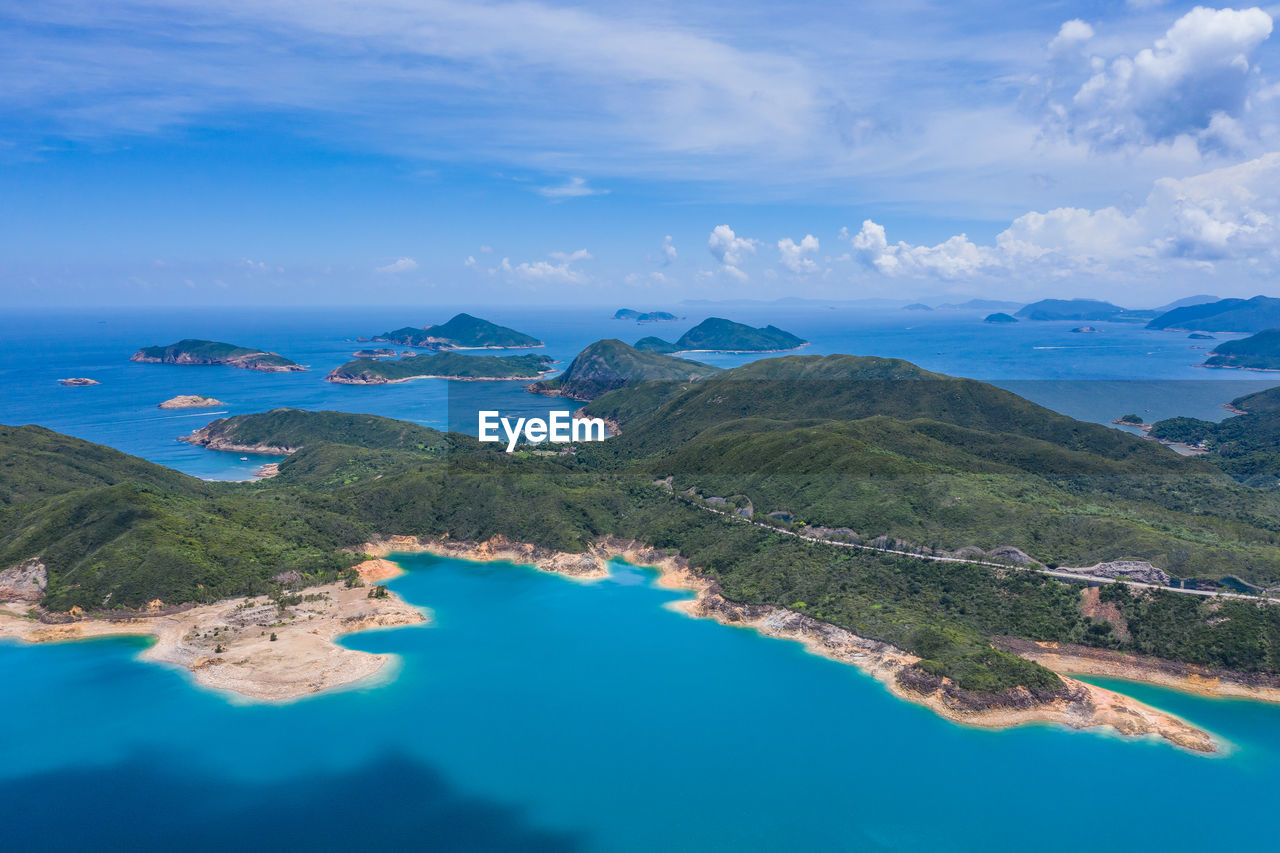 Aerial view of sea and mountains against blue sky