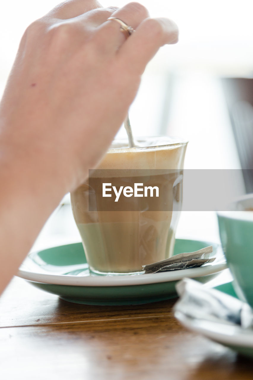 CLOSE-UP OF HAND HOLDING COFFEE CUP