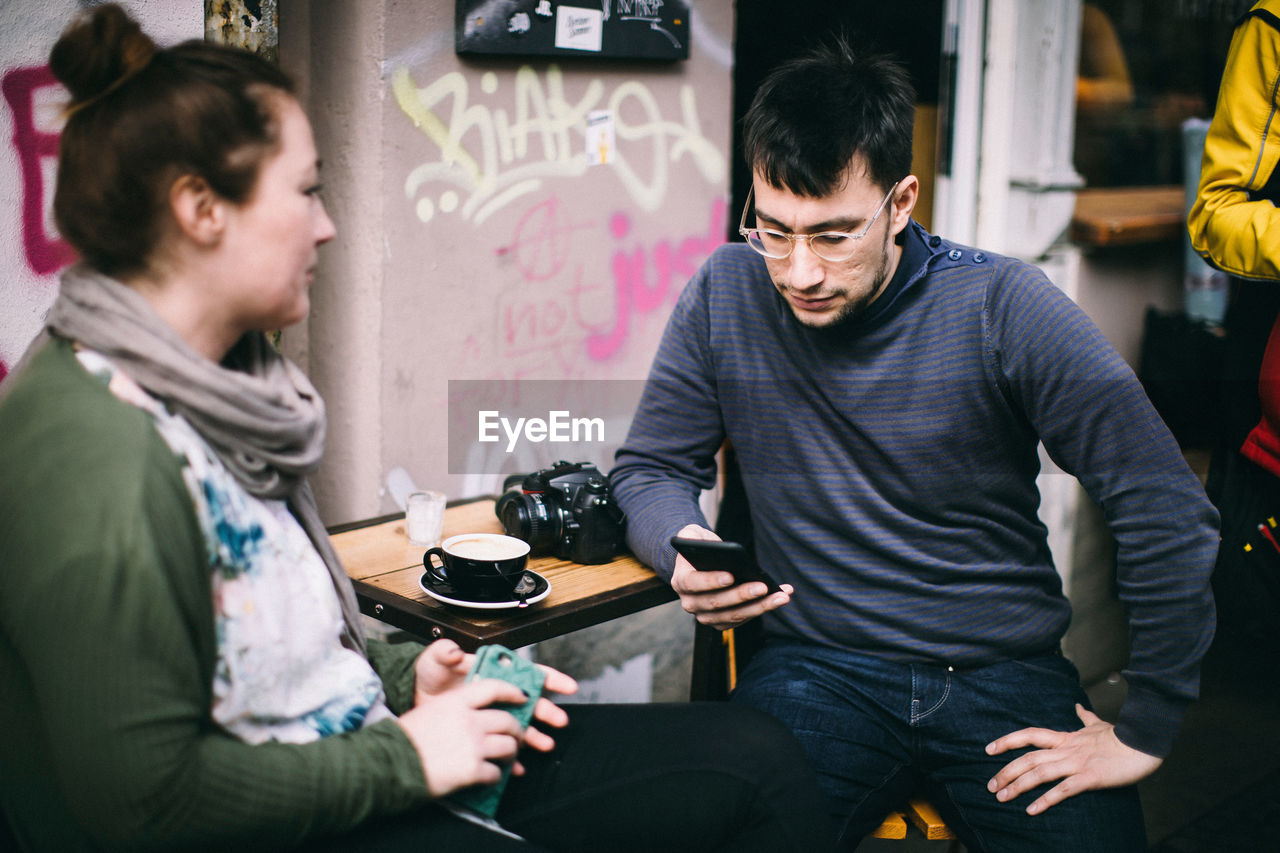 MAN AND WOMAN USING PHONE WHILE STANDING IN OFFICE