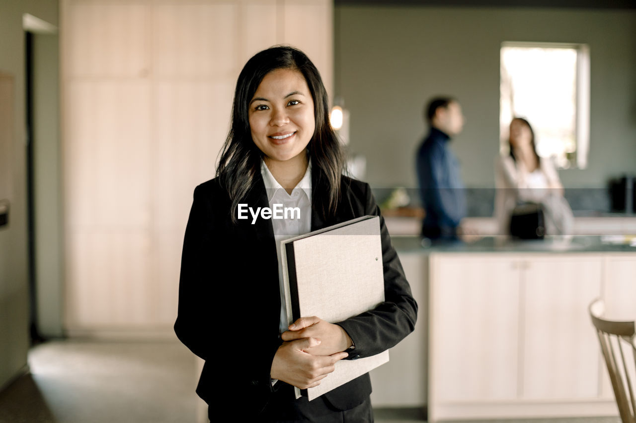 Portrait of saleswoman with folder standing at new home