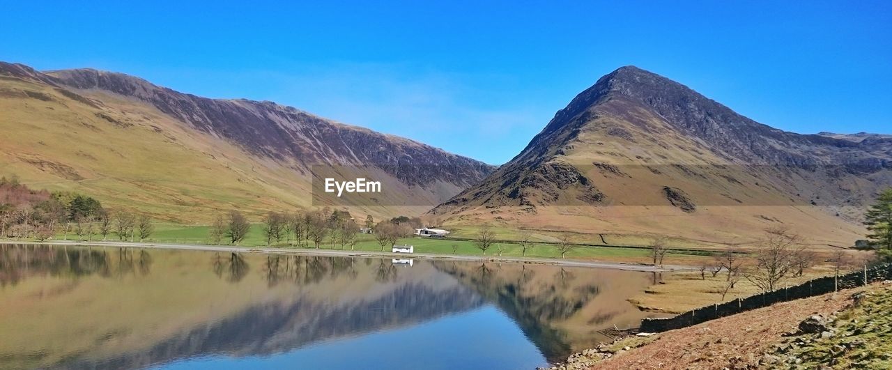 Panoramic view of lake and mountains against blue sky