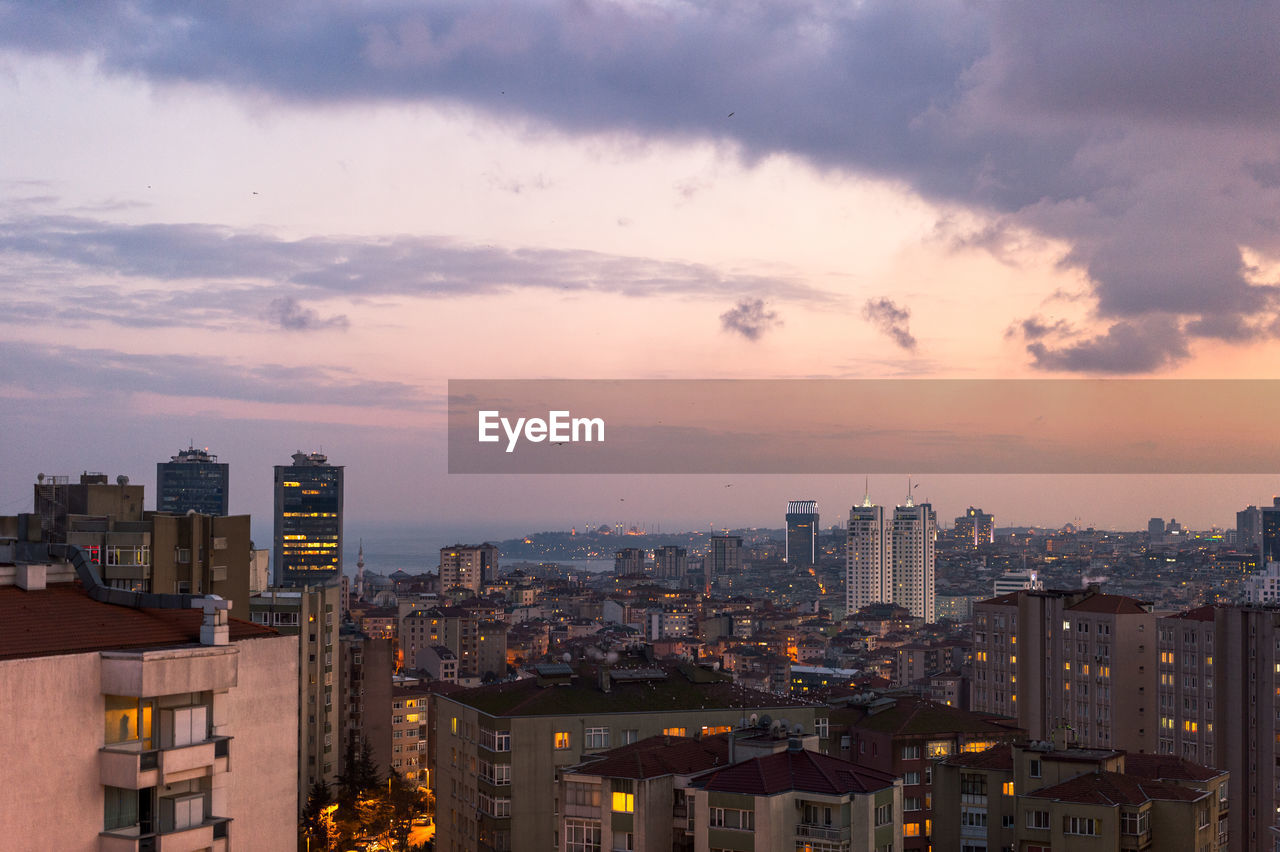 Illuminated cityscape against sky at dusk