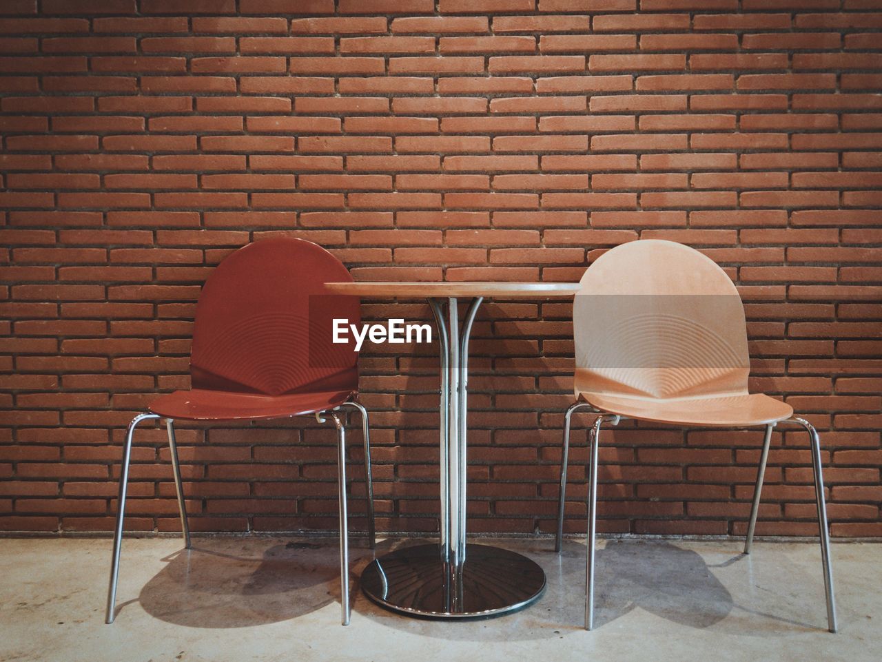 Empty chairs against brick wall at cafe