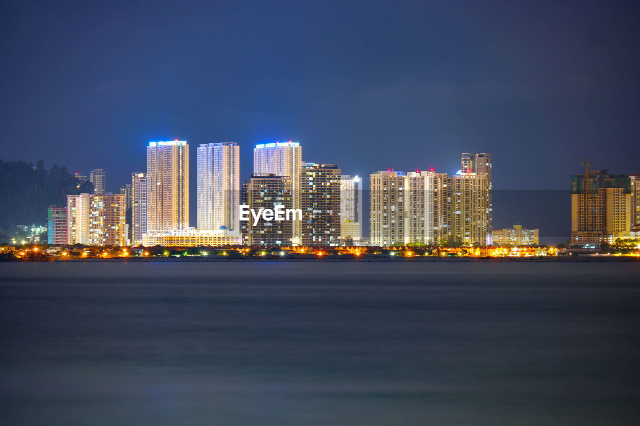 Illuminated buildings in city against sky at night