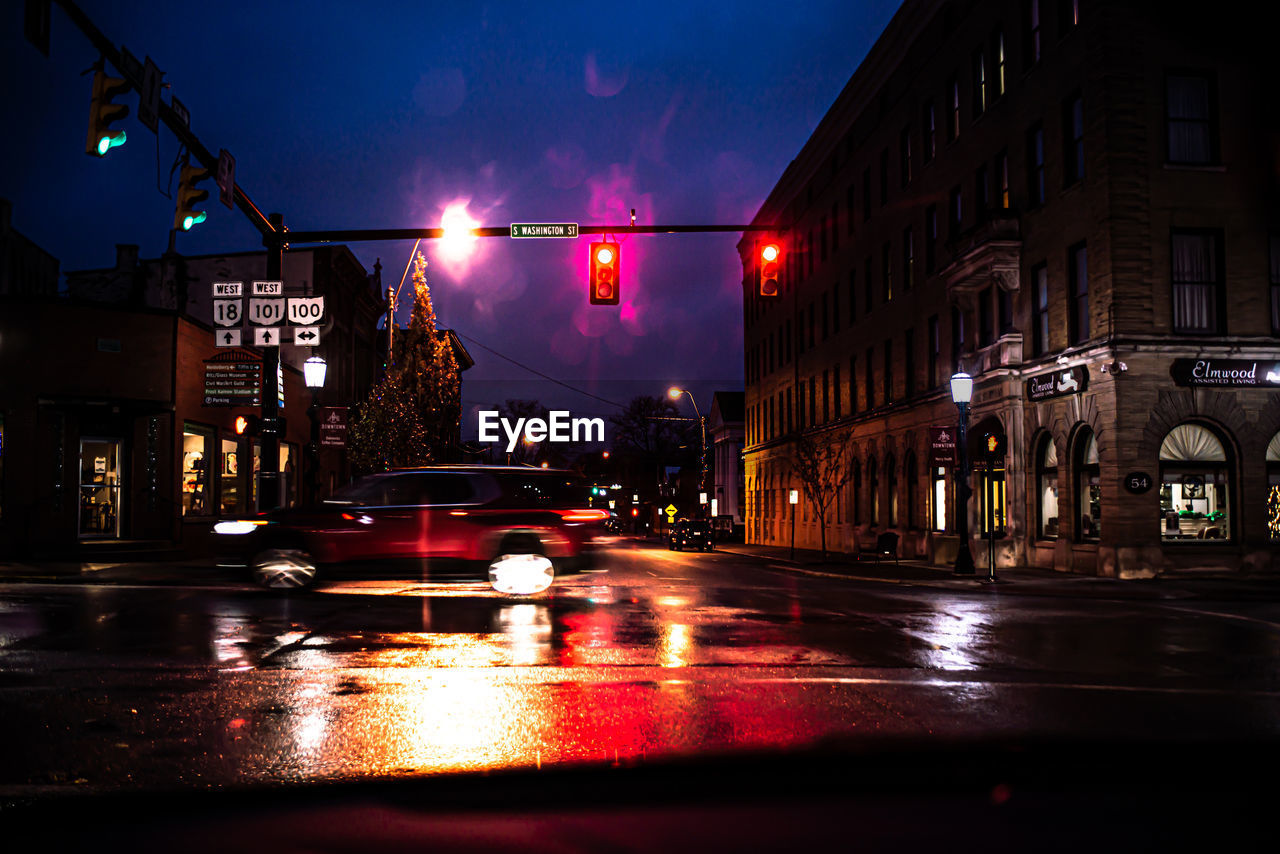 ILLUMINATED CITY STREET AMIDST BUILDINGS AT NIGHT