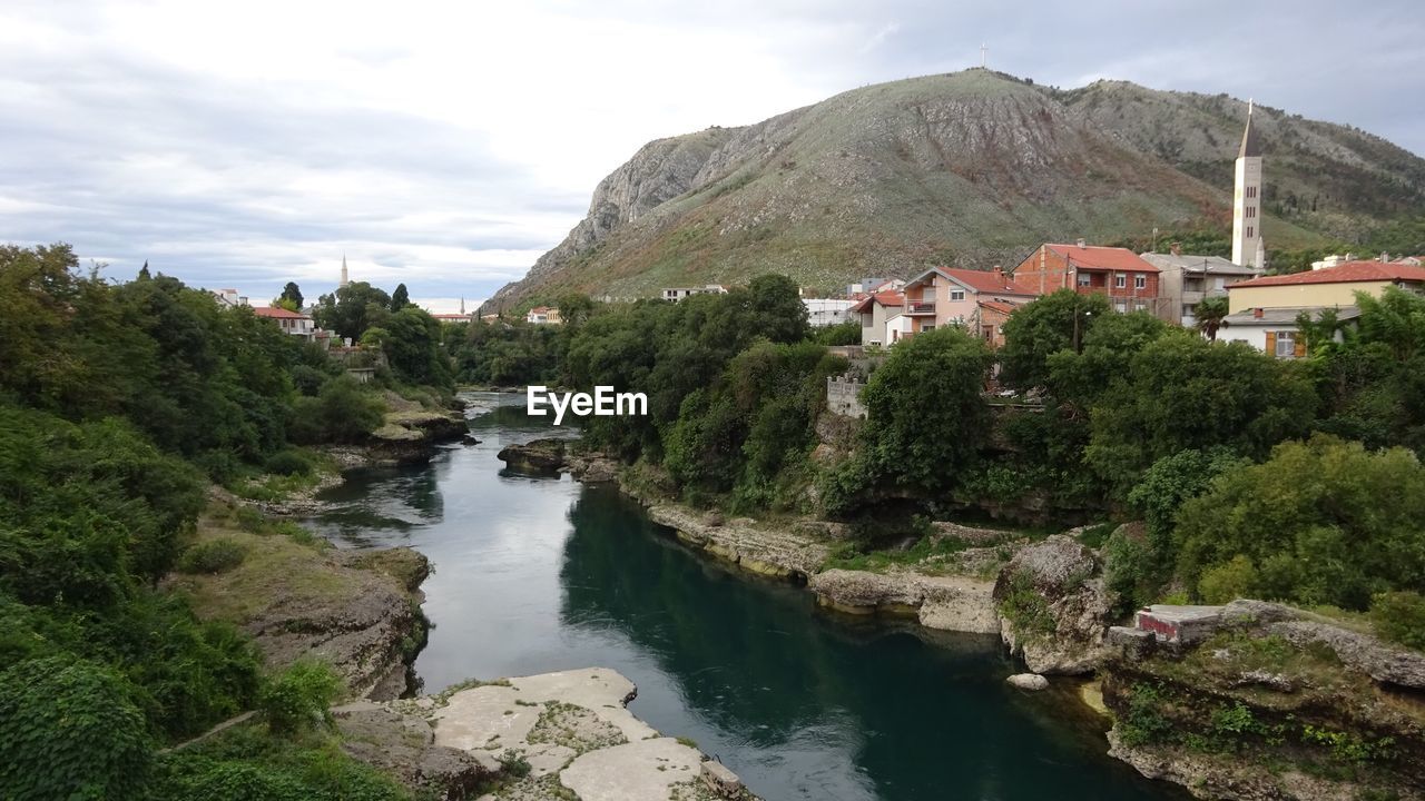 River amidst trees and buildings against sky