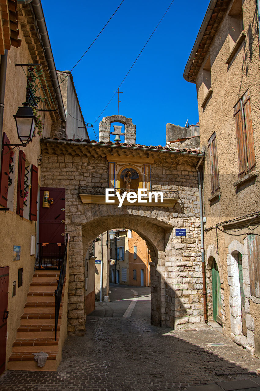 ALLEY AMIDST BUILDINGS IN CITY AGAINST SKY