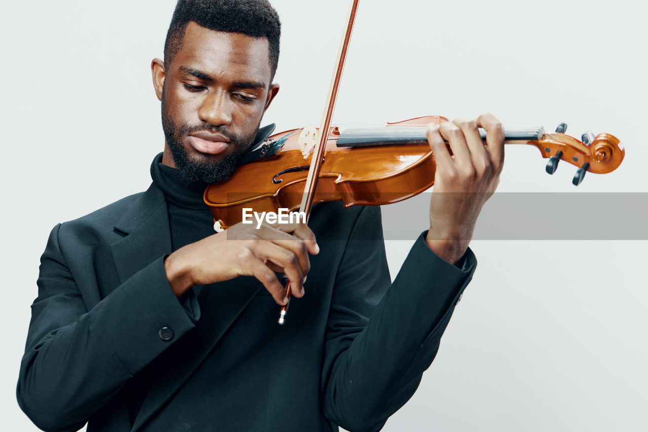 midsection of businessman playing violin against white background