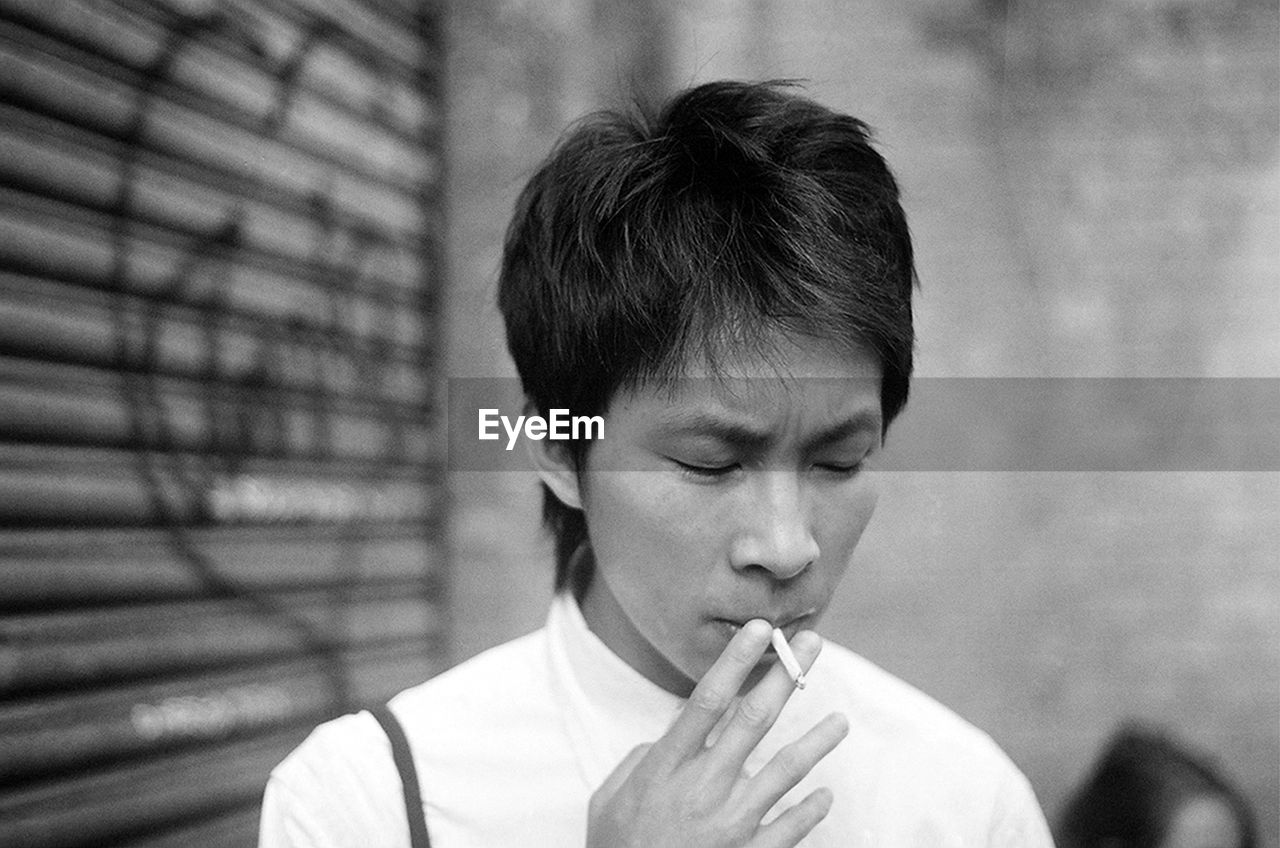 Close-up of man smoking against wall