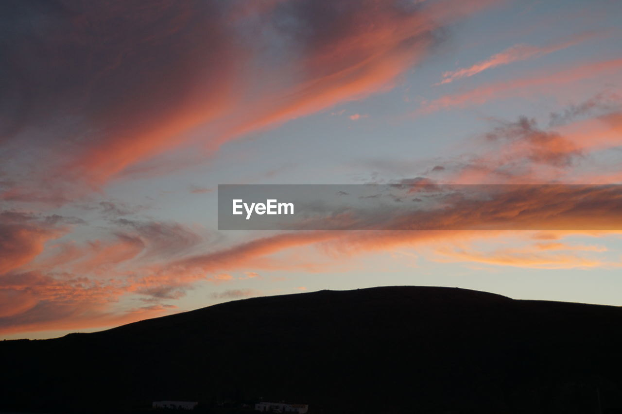 LOW ANGLE VIEW OF DRAMATIC SKY OVER SILHOUETTE MOUNTAINS