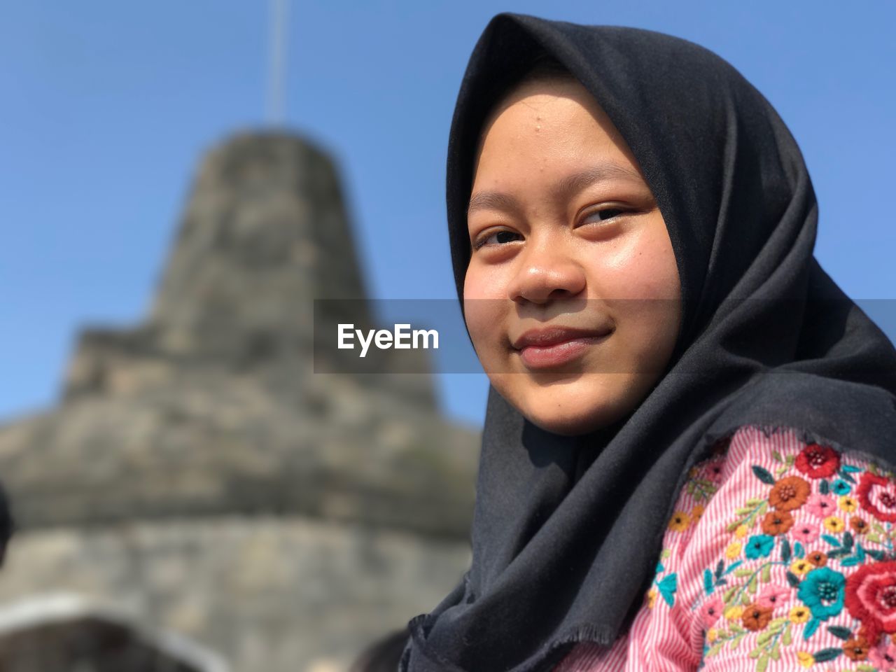 Low angle portrait of young woman against stupa at mertoyudan