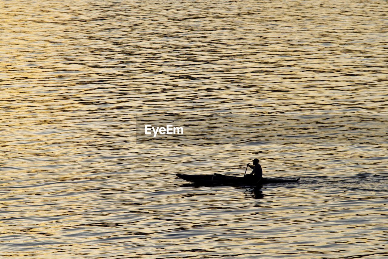 High angle view of silhouette man sailing boat in sea