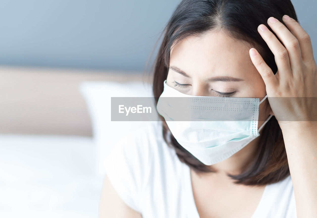 Mid adult woman wearing flu mask at home