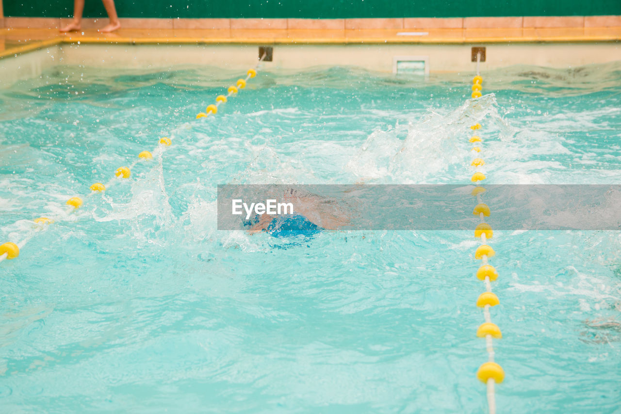 PEOPLE SWIMMING IN POOL BY WATER